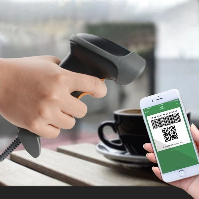 Handheld barcode scanner reading a payment QR code from a customer's phone screen at a cafe counter