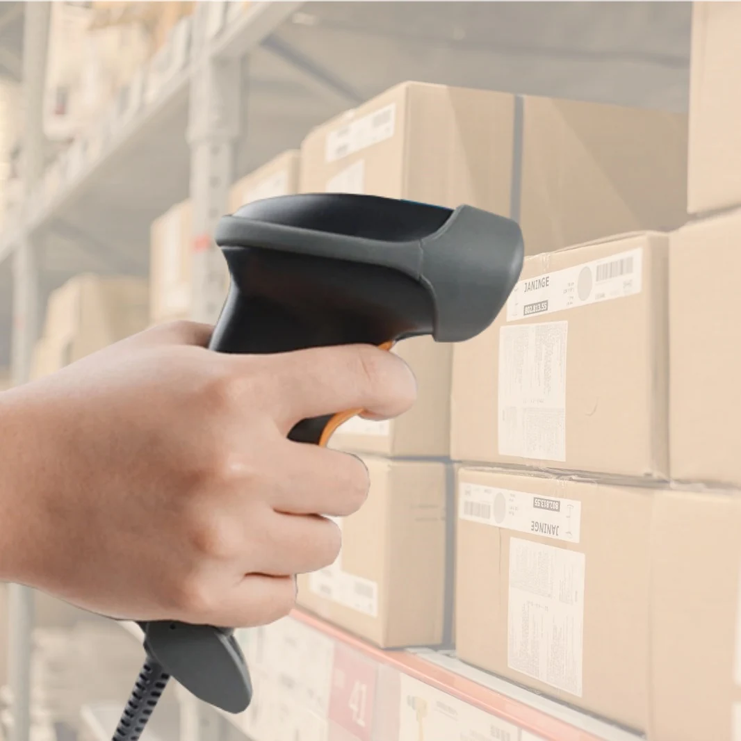 Operator scanning a carton label on a warehouse racking aisle with a handheld 2D barcode scanner