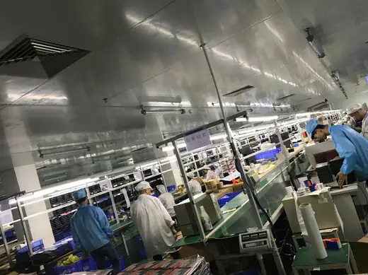 The assembly floor under full lighting, with operators working along both sides of the line.
