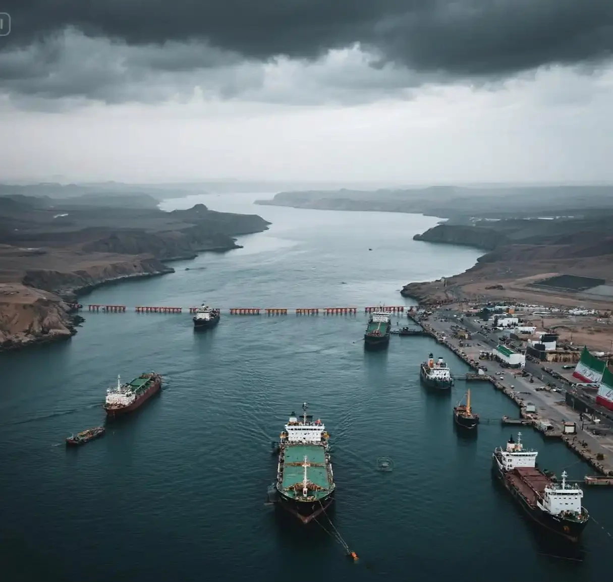 Aerial view of tankers anchored along a narrow strait under heavy cloud