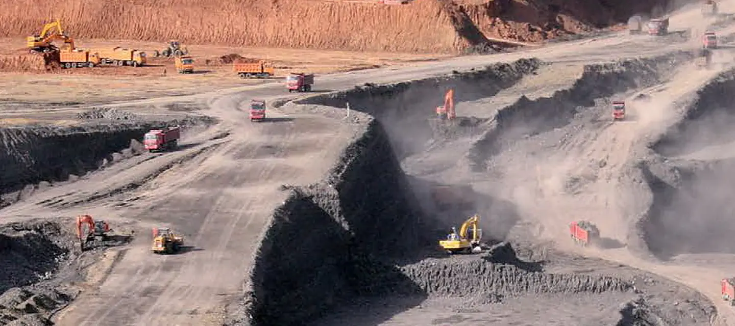 Excavators and haul trucks working a quarry face on a graded bench