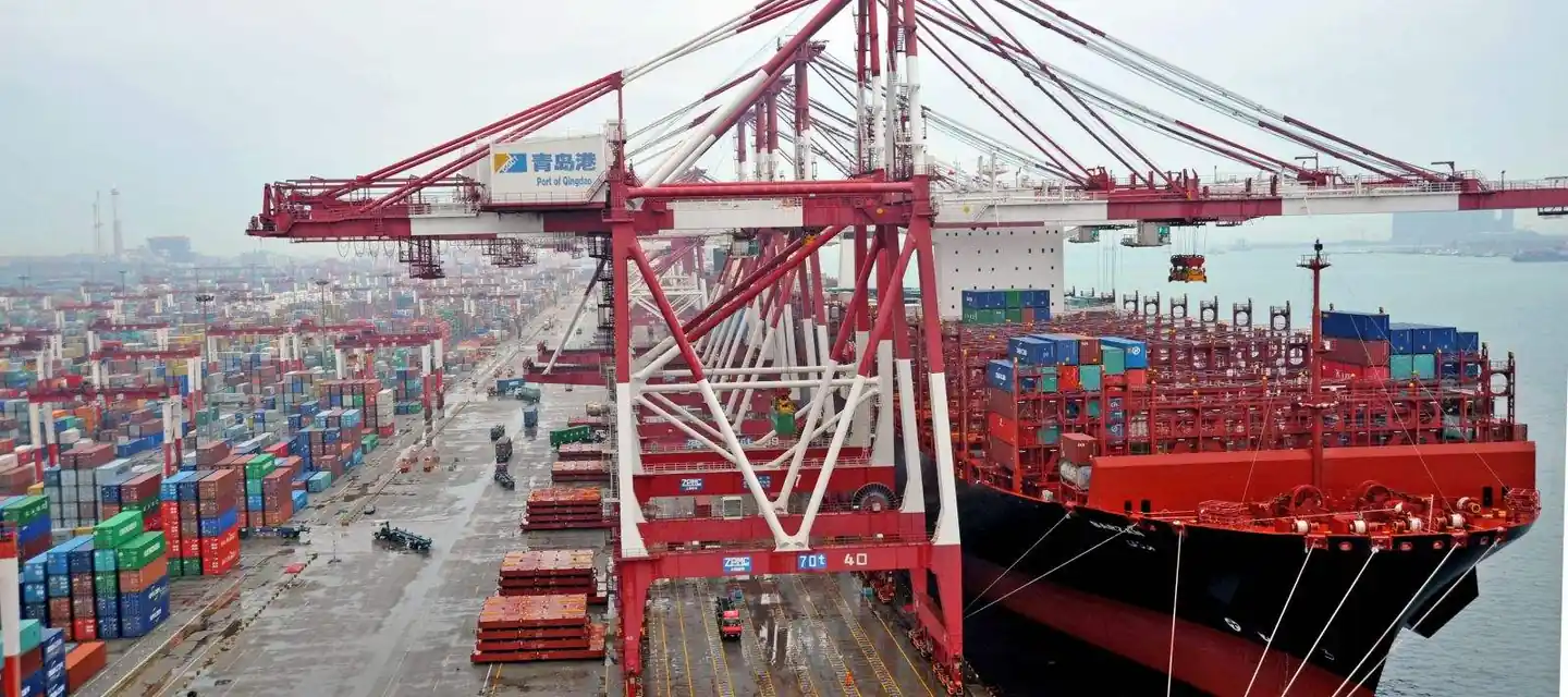 Container ship loading under red gantry cranes at Qingdao Port