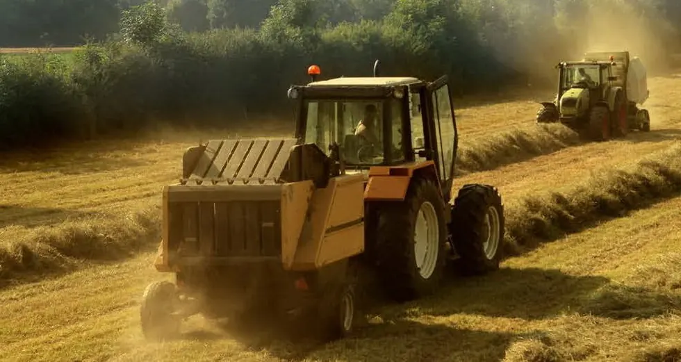 Tractors baling in a field of cut grass