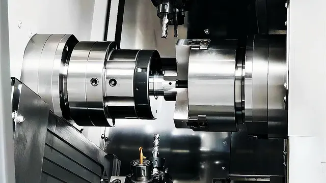 Bright steel component held in a CNC lathe chuck during machining