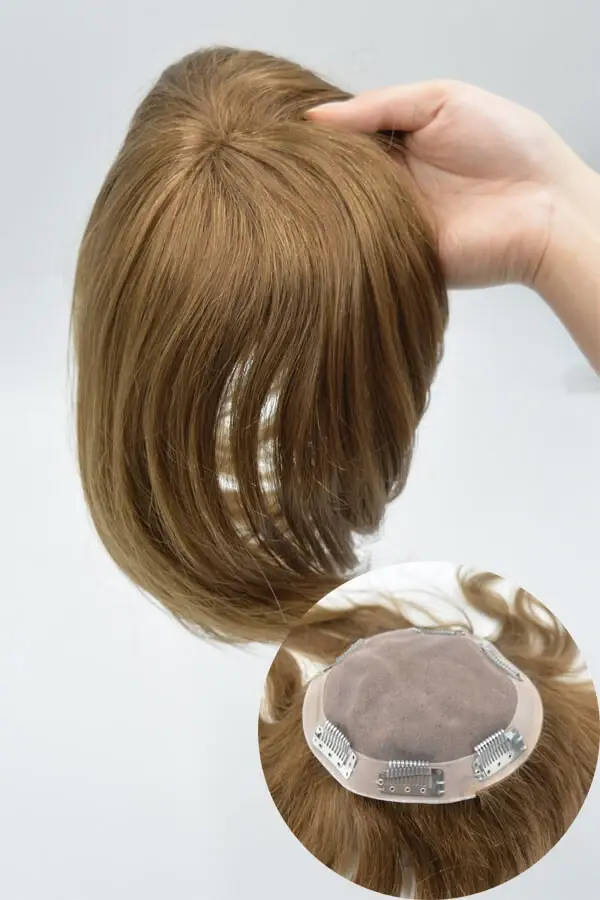 Women's hair replacement unit shown from above with the front hairline visible and natural parting
