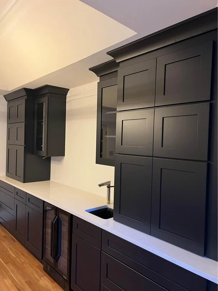 Dark painted shaker kitchen run with wall cabinets and a pale worktop