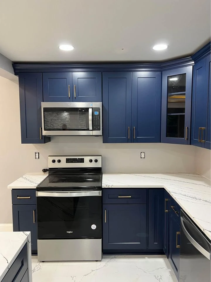Completed shaker kitchen installation with a stone island top and full height wall cabinets