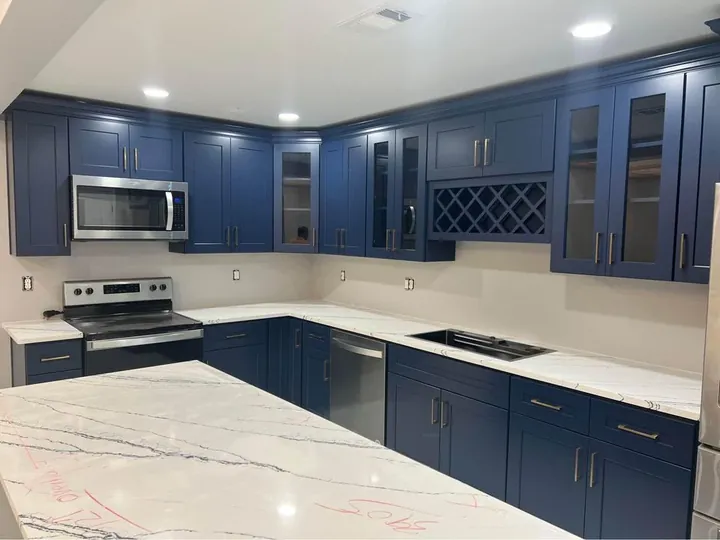 Completed shaker kitchen installation with a stone island top and full height wall cabinets