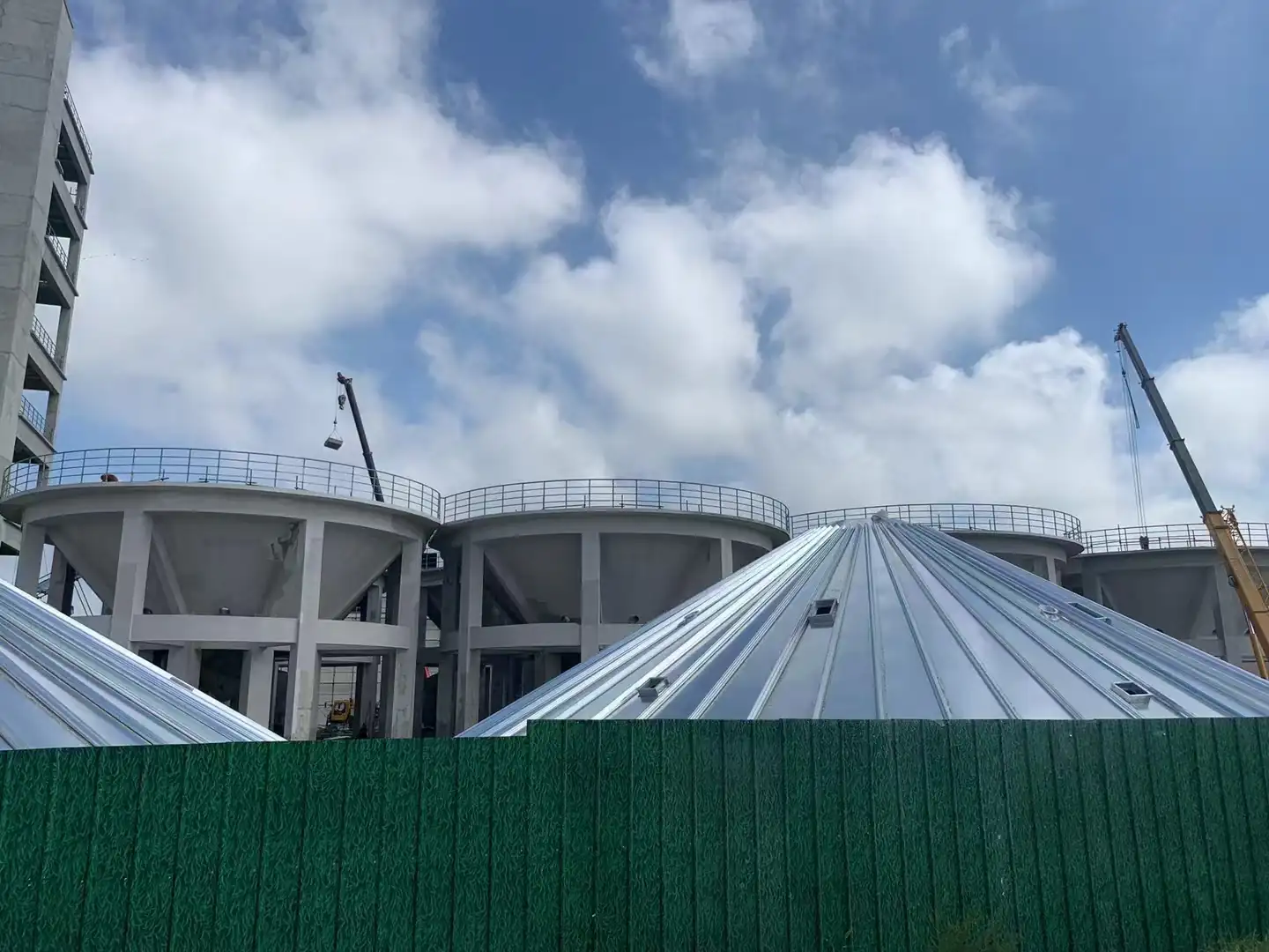 Galvanized steel silos with conical roofs under construction at a storage site