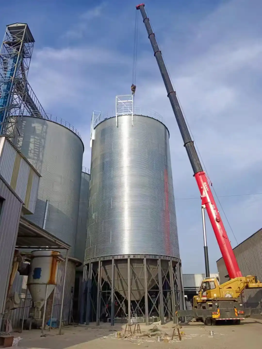Hopper bottom galvanized silos raised on steel legs above a discharge point