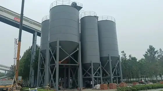 Steel silos on raised concrete supports with a conveyor bridge under construction