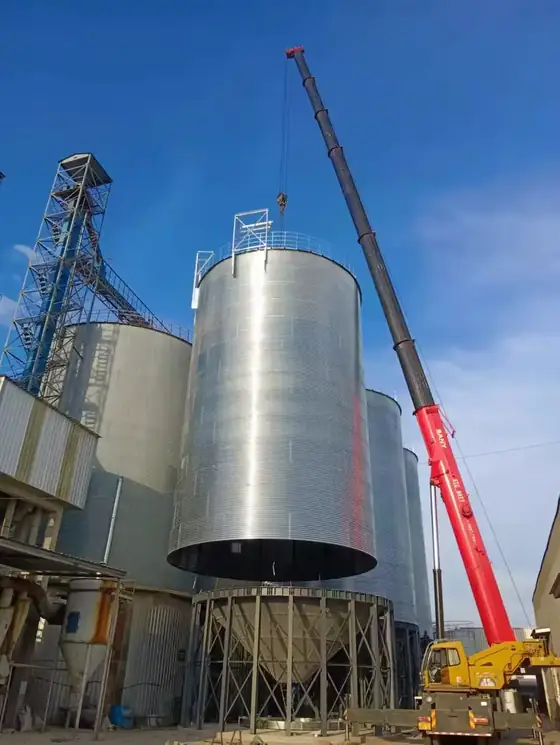 Silo group under erection with a crawler crane lifting a shell section