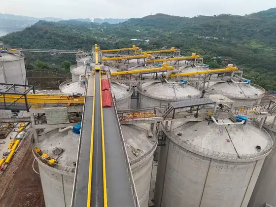 Concrete silo structure under construction with steel silos alongside