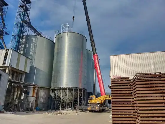 Crawler crane lifting silo sections during erection of a galvanized silo battery