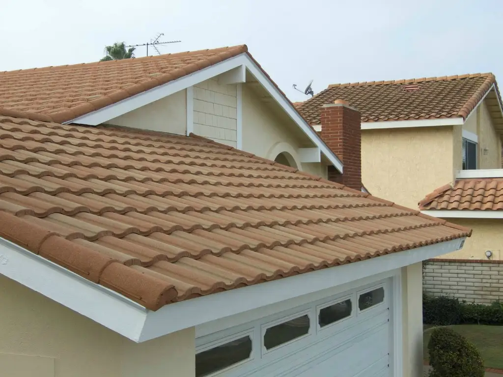 Residential roof laid with terracotta classical roof tiles above a white garage