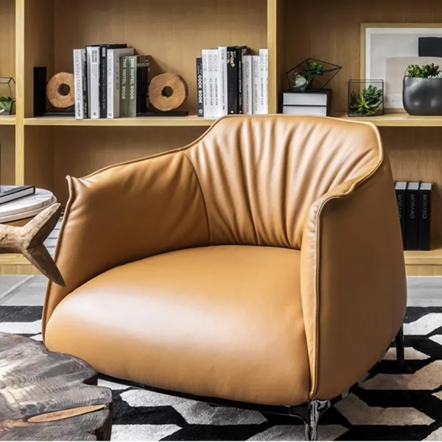 Tan leather armchair with gathered backrest in a modern room with a wood bookshelf.