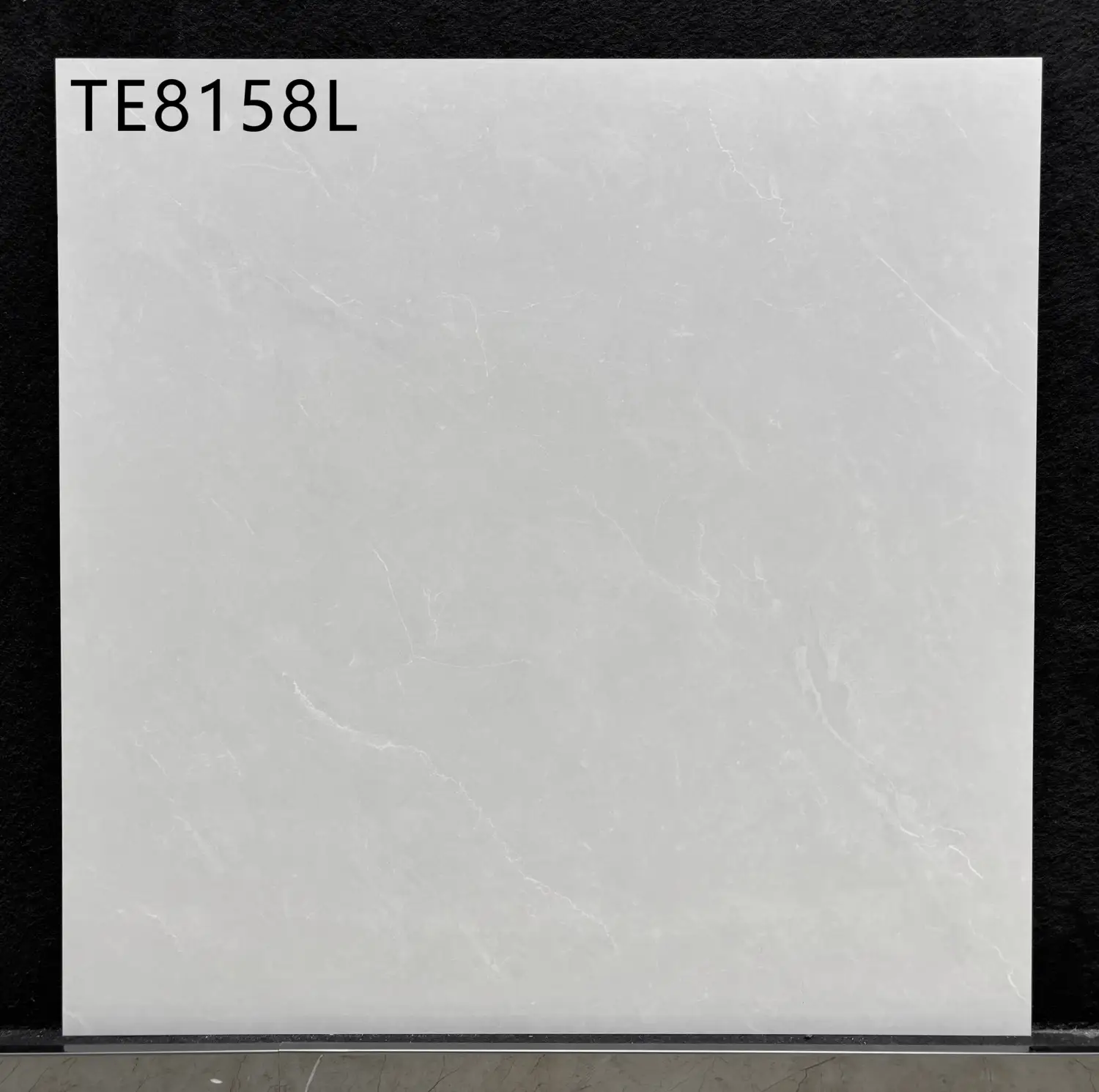 Square white marble-look floor tile with subtle grey veining and code TE8158L.