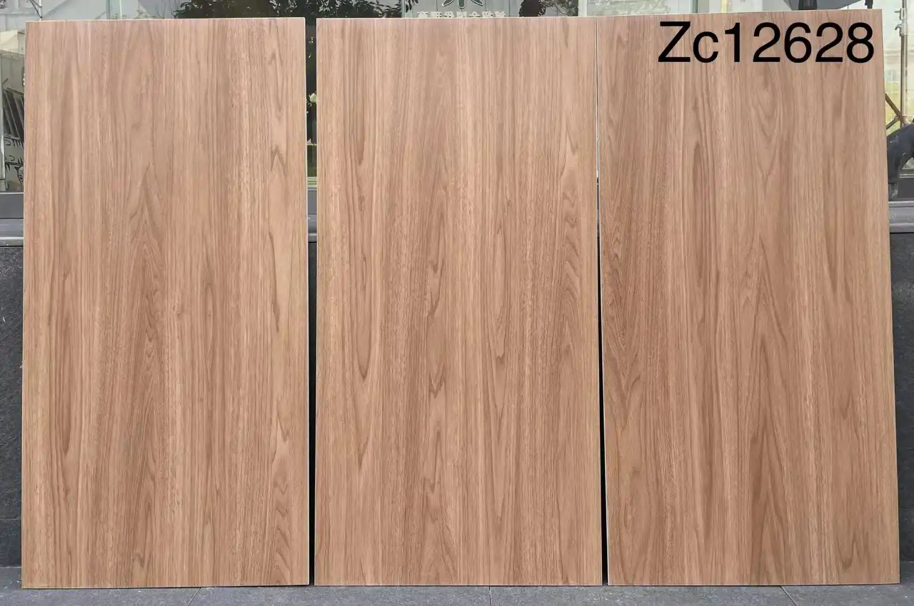 Three wood-grain ceramic tiles standing upright, showcasing a light brown oak texture.