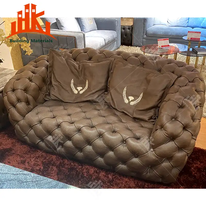 A brown tufted leather sofa with embroidered pillows sits on a rug.