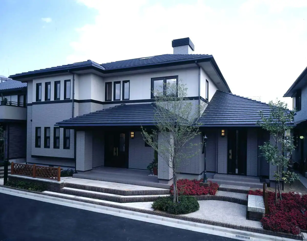 Two-storey house finished with dark stone-coated metal roof tiles and light grey walls