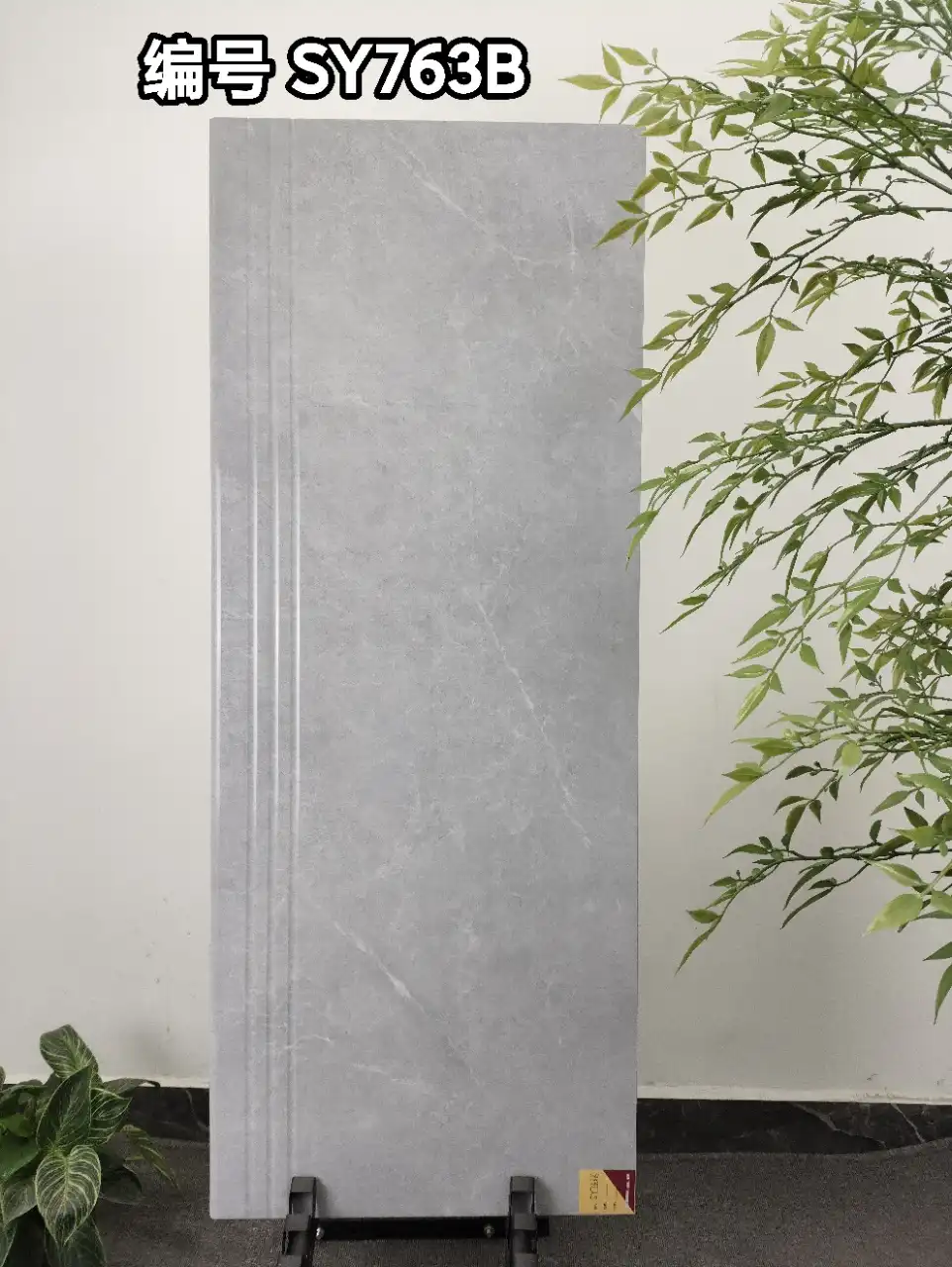 Vertical gray stone-look tile with grooved edges displayed on a stand.