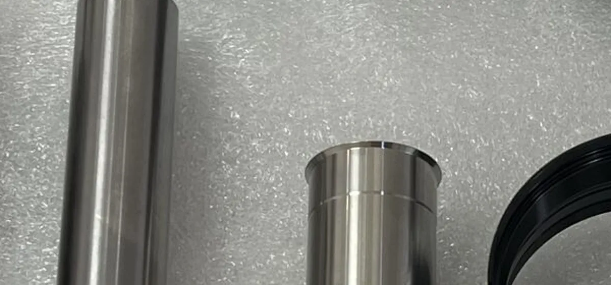 Turned stainless steel shafts bushings and rings laid out on a workbench