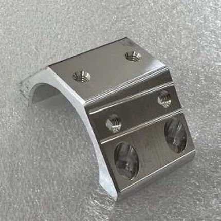 Machined aluminium saddle tube clamp with a curved seat and four counterbored fixing holes