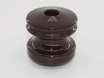 A brown ceramic insulator with a central hole and grooved middle section against a white background.