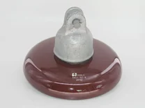 Close-up of a brown porcelain electrical insulator with a metal cap and eyelet.