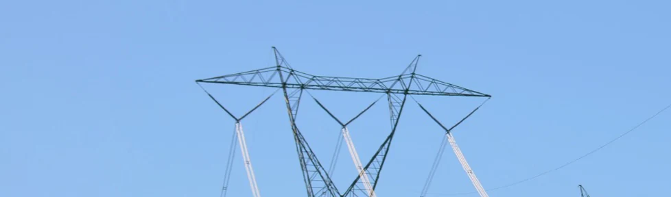 Steel lattice transmission towers carrying conductors against a clear sky