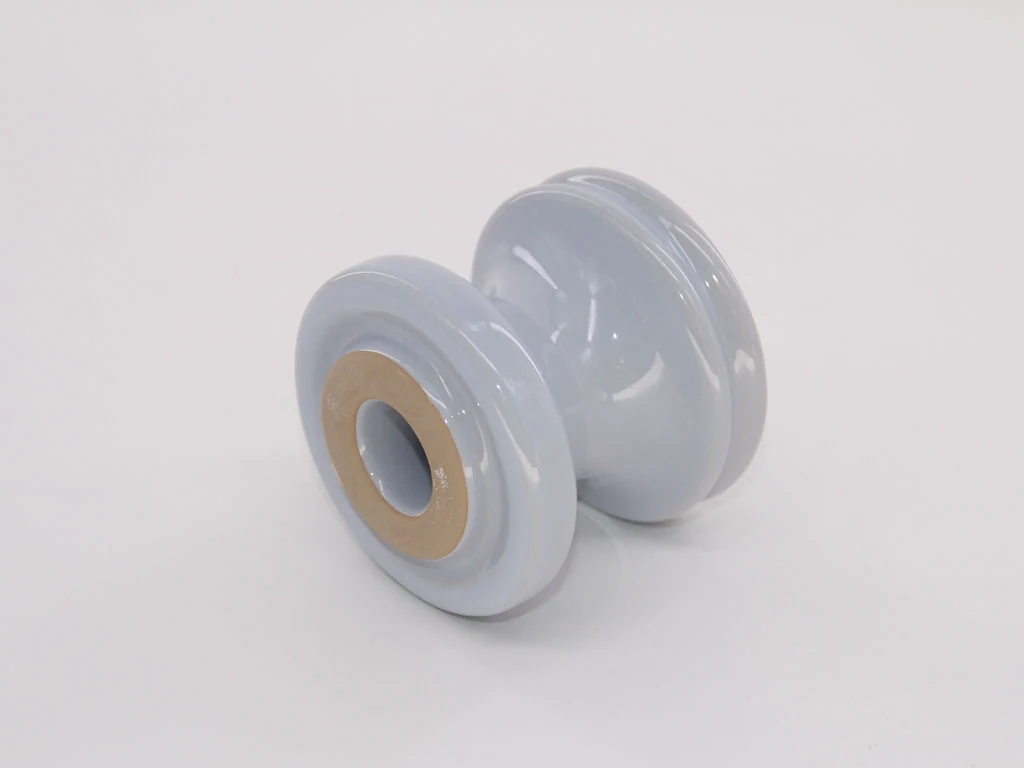 White glazed ceramic spool insulator with a central mounting hole on a plain white background