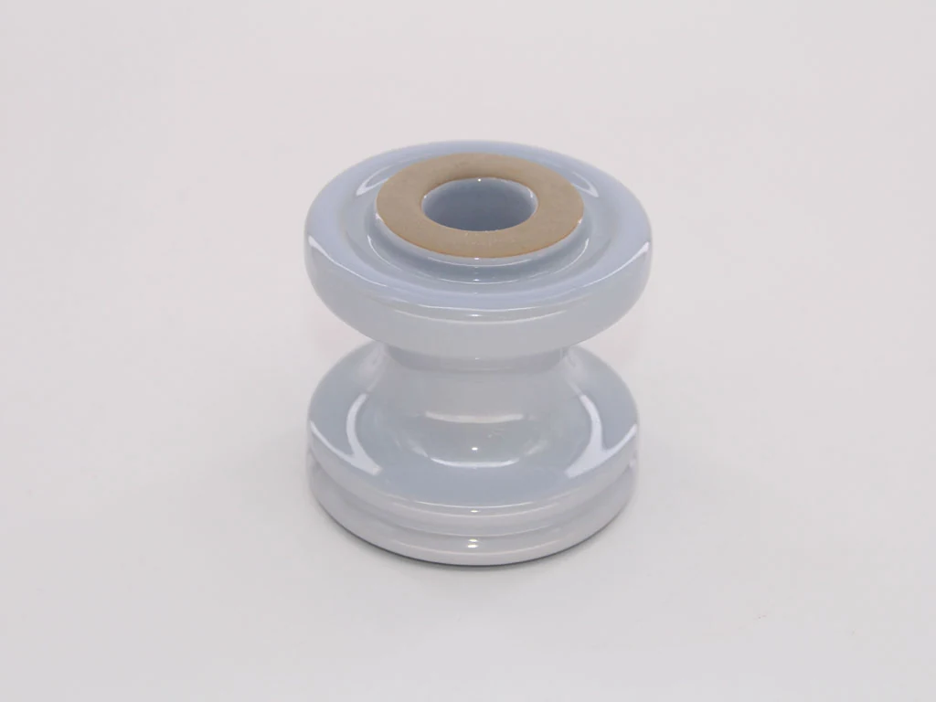 Glossy white glazed ceramic insulator with brass threaded metal insert on top, centered on a plain white background