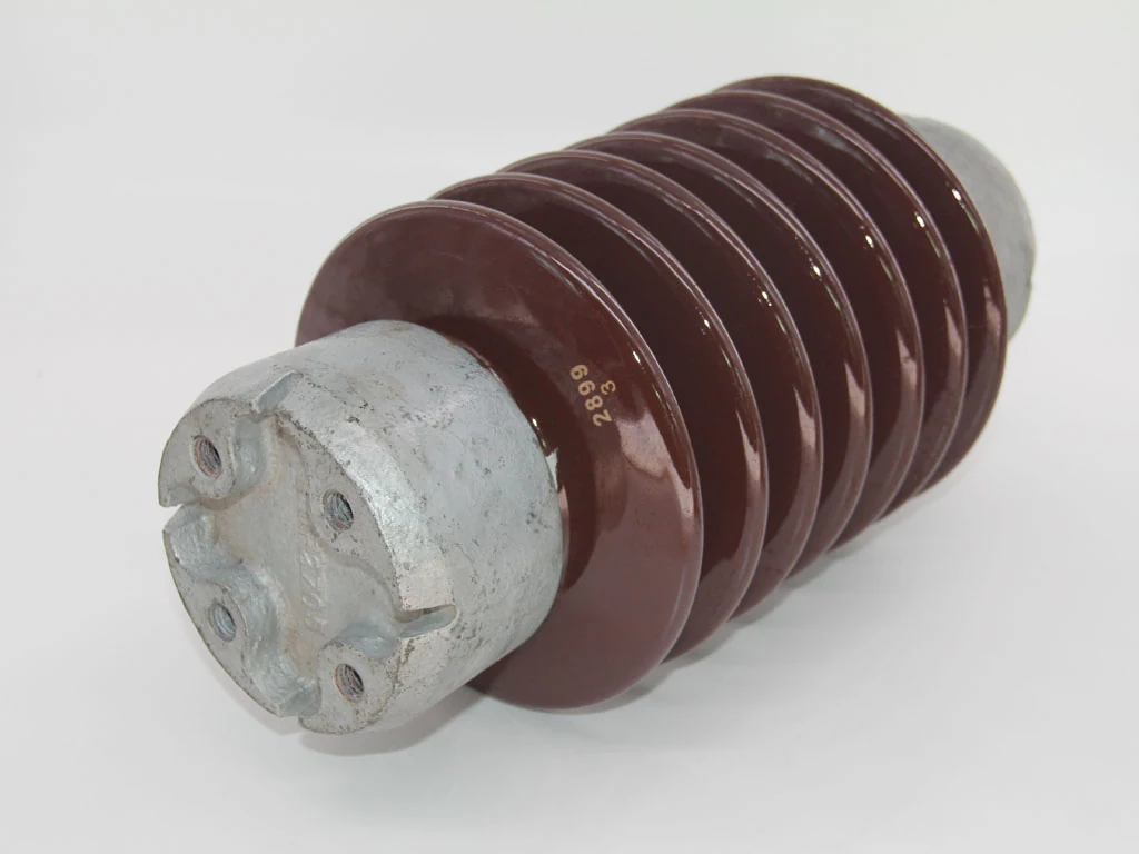 Brown porcelain electrical insulator with metal mounting base lying on white background