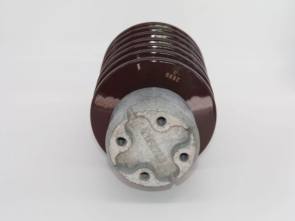 Brown ribbed porcelain insulator with cast metal mounting cap and bolt holes, shown end-on against a