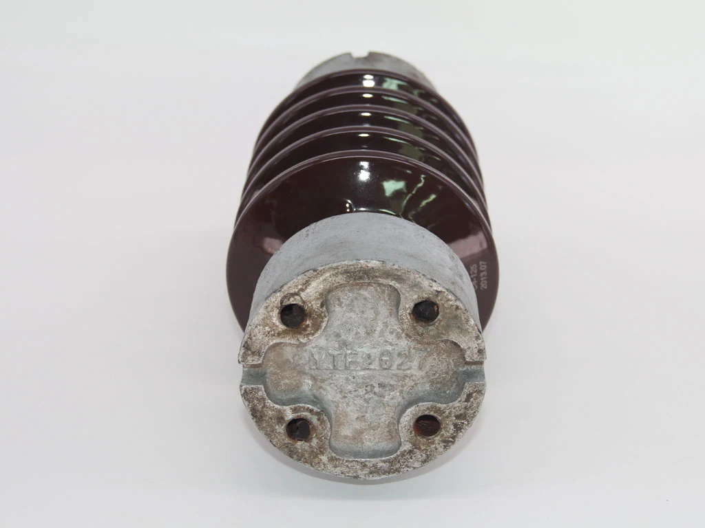 Brown ceramic electrical insulator with cast metal mounting cap and bolt holes on a plain white background