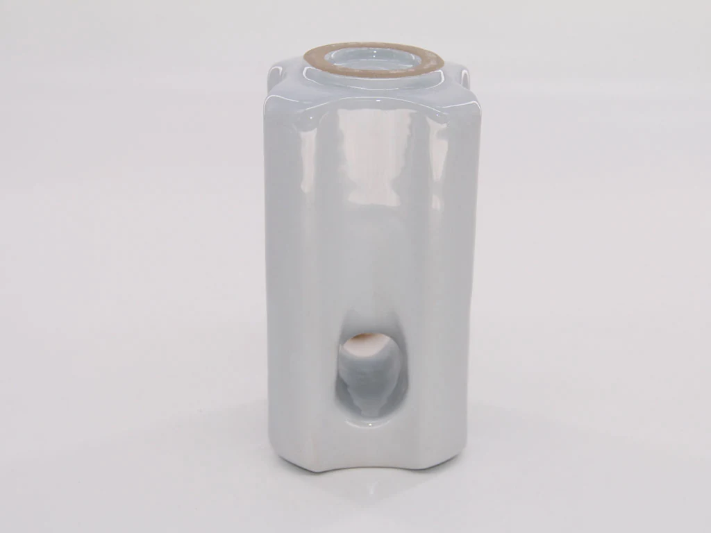 White glazed porcelain insulator with ribbed body and metal top ring, centered on a plain light background