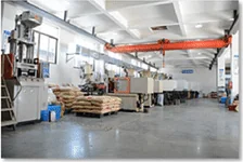 Nave de inyección de plástico con puente grúa y materia prima en pallets a pie de máquina.