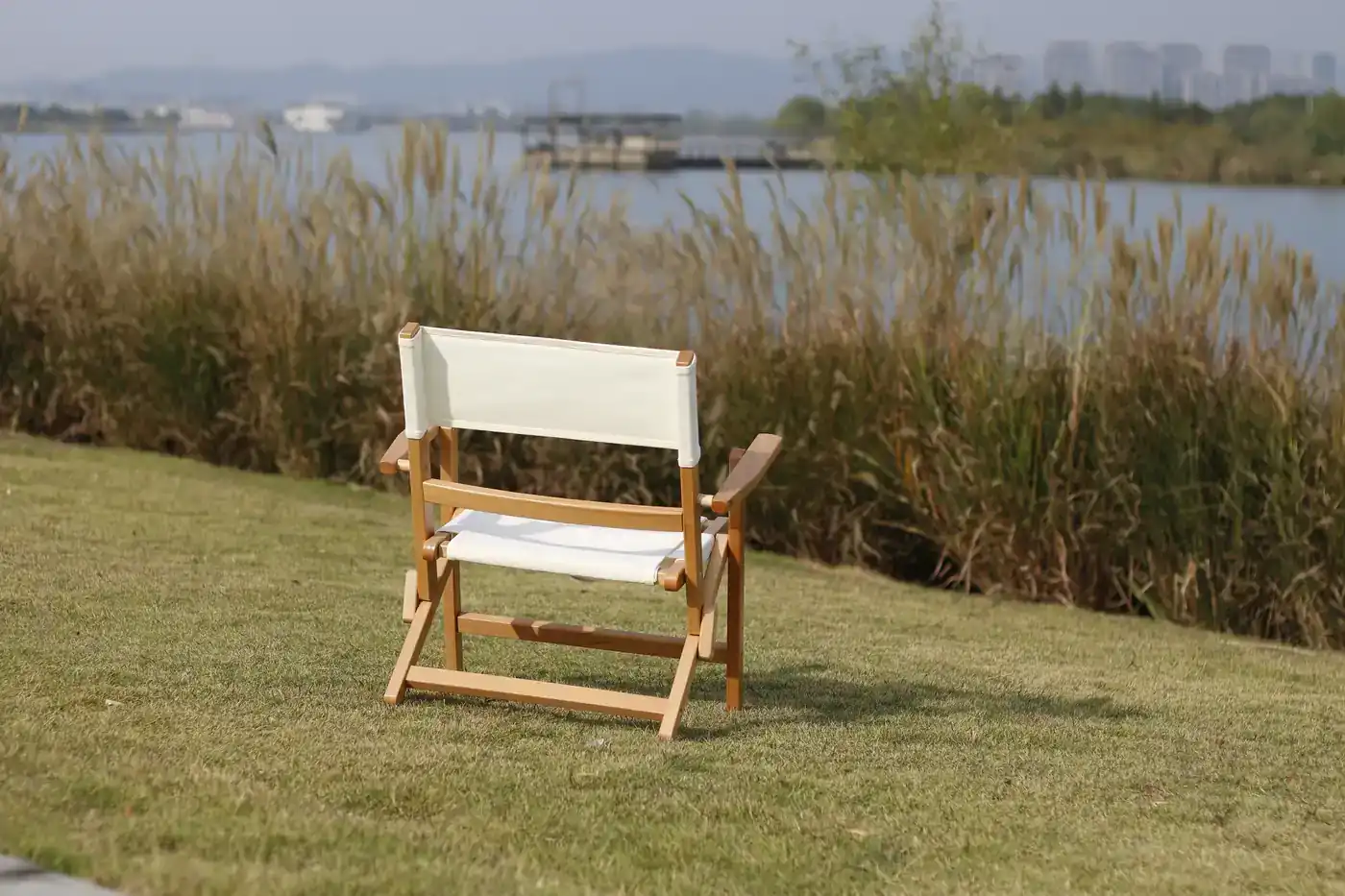 Mango solid wood folding camping chair set up on grass beside a lake