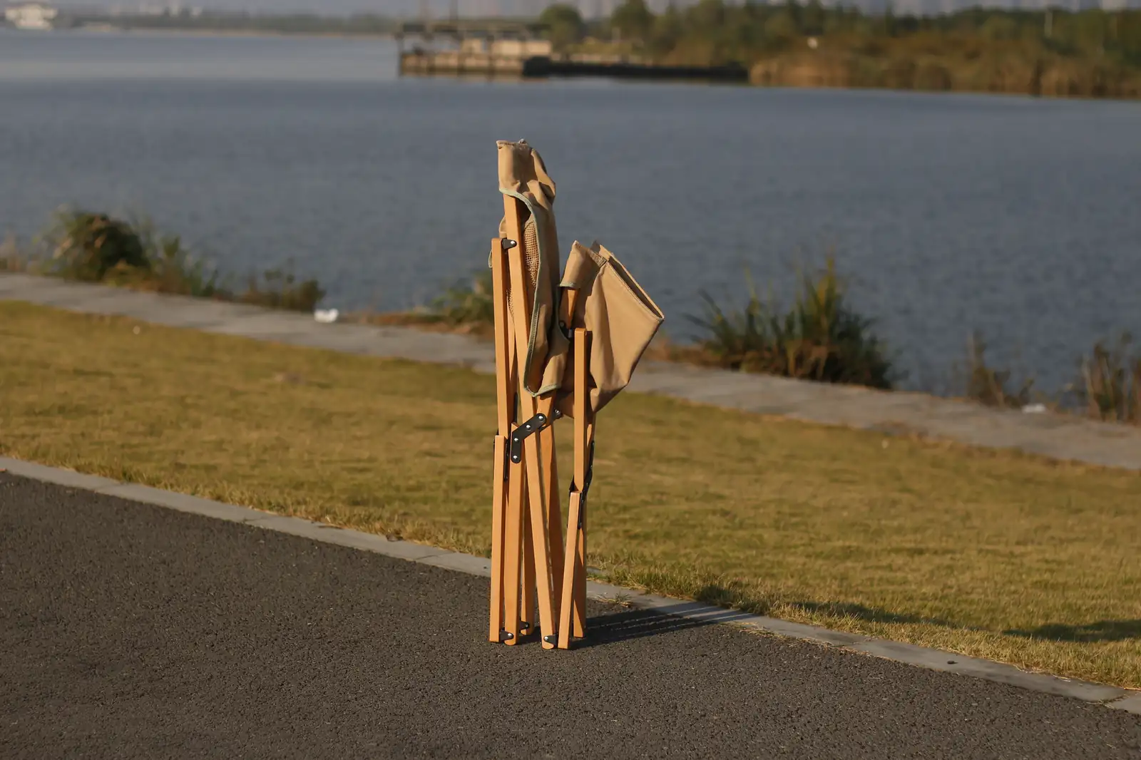 Mango wooden folding chair folded upright on a lakeside path