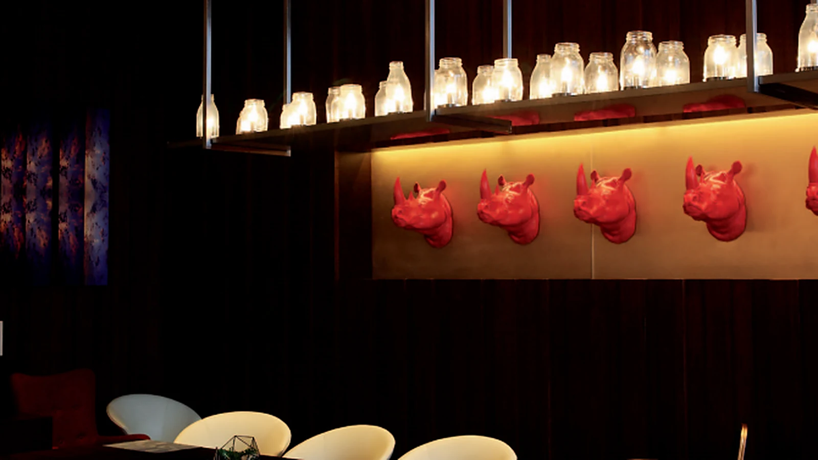 Glass jar pendant lights above a dark restaurant bar counter
