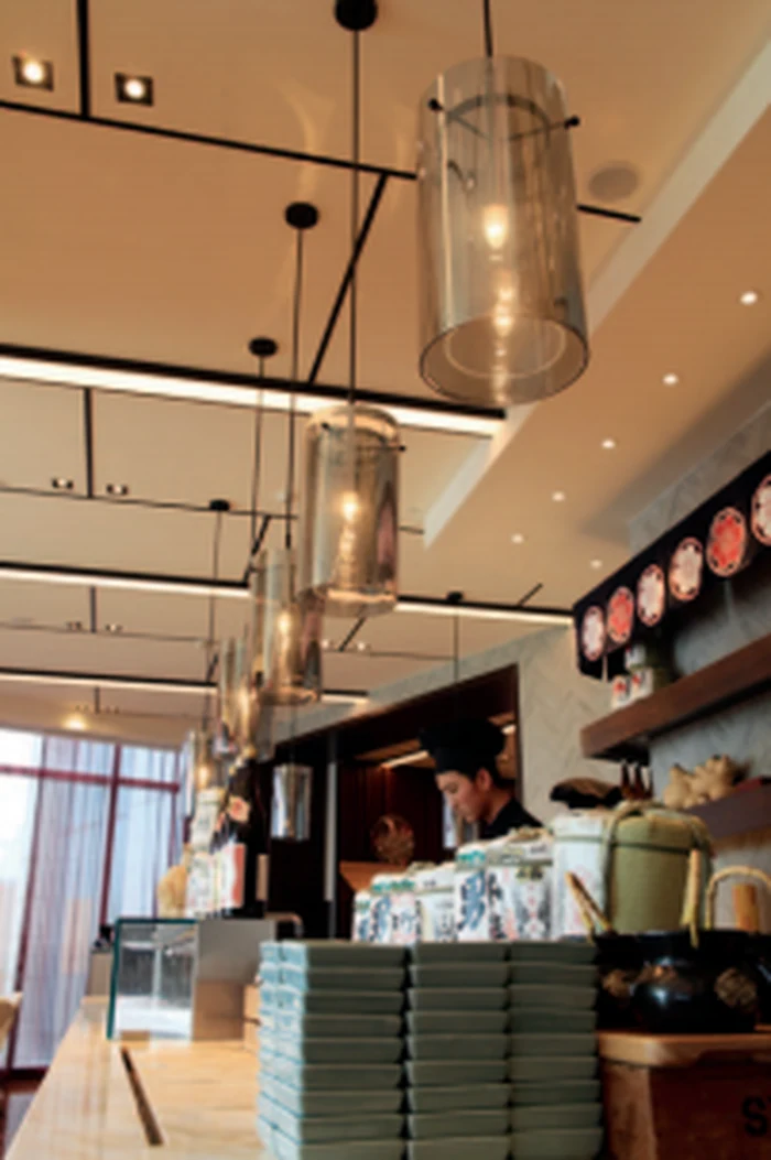 Clear glass cylinder pendant lights above a cafe counter