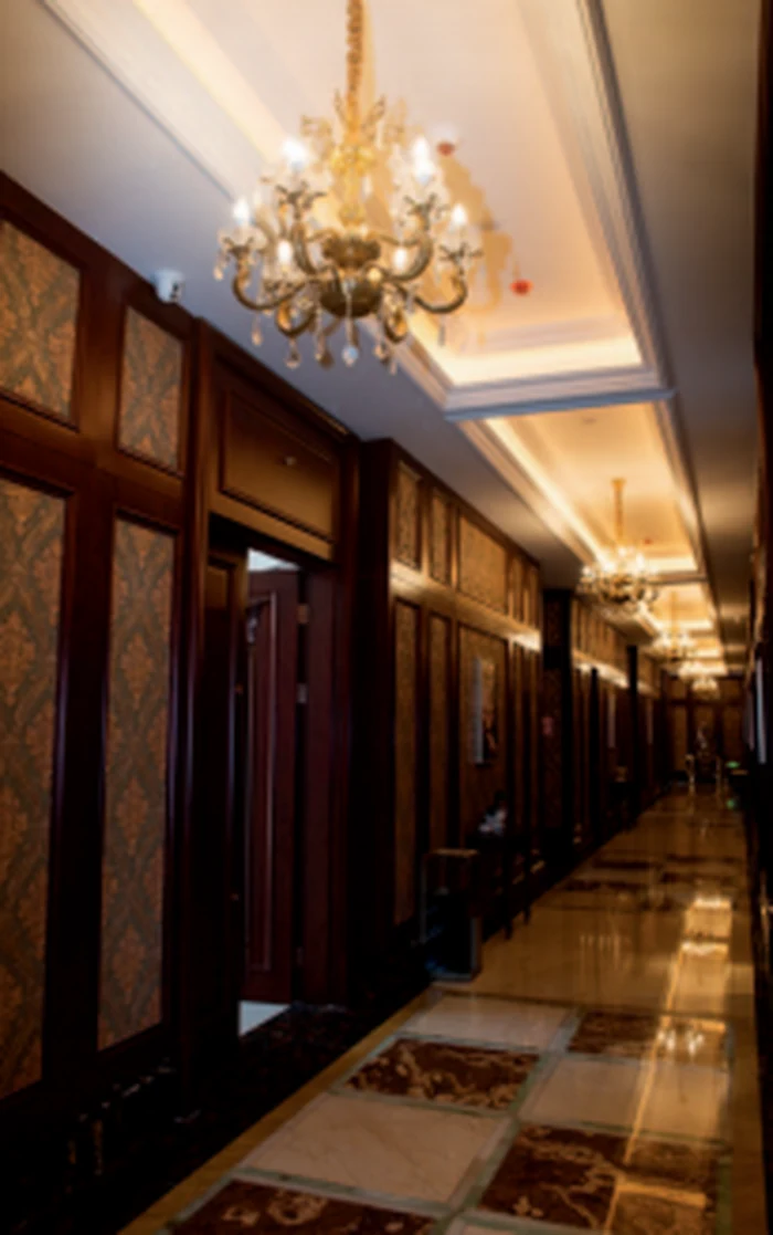 Line of gold chandeliers down a hotel corridor with panelled walls