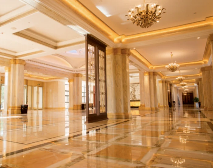 Gold chandeliers in a marble hotel lobby with columns