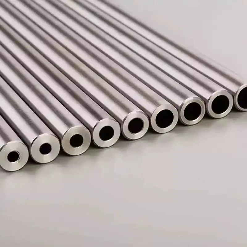 Row of polished hollow metal tubes with varying diameters arranged diagonally on a plain gray surface