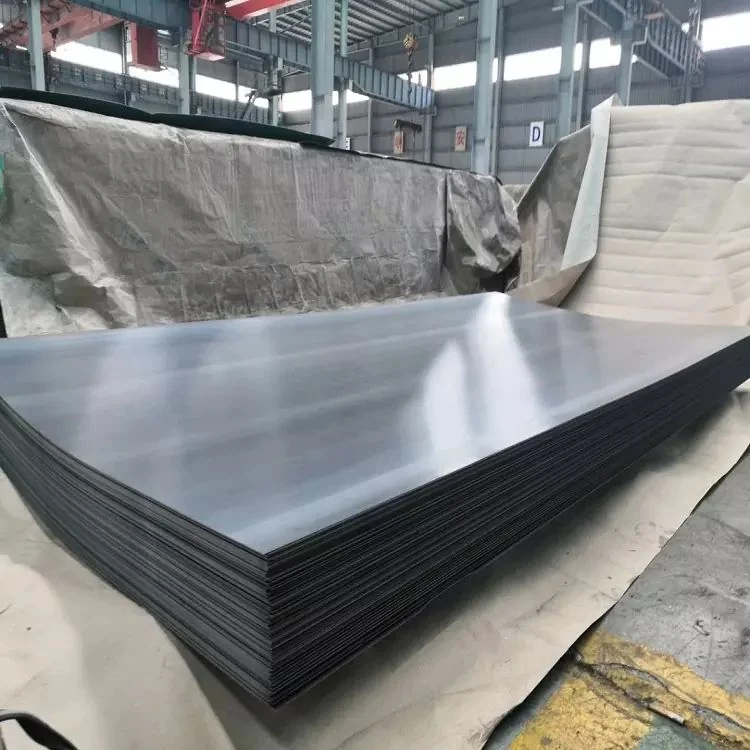 Large stack of dark metal sheets on the floor of an industrial warehouse