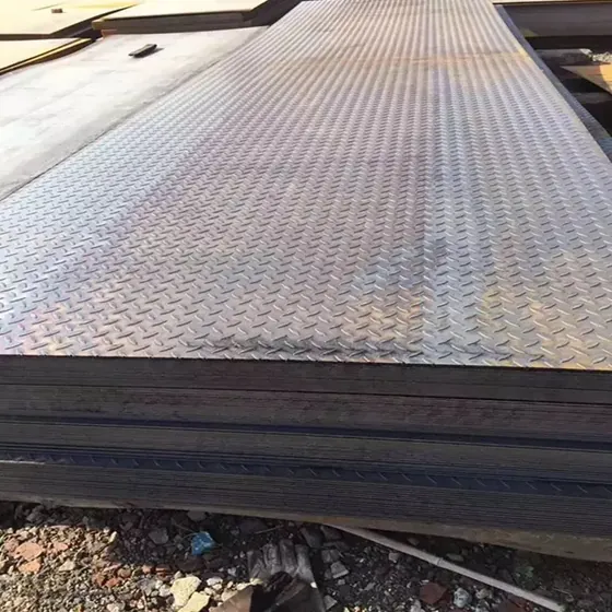 Stacked diamond-pattern steel checker plates stored outdoors on gravel ground