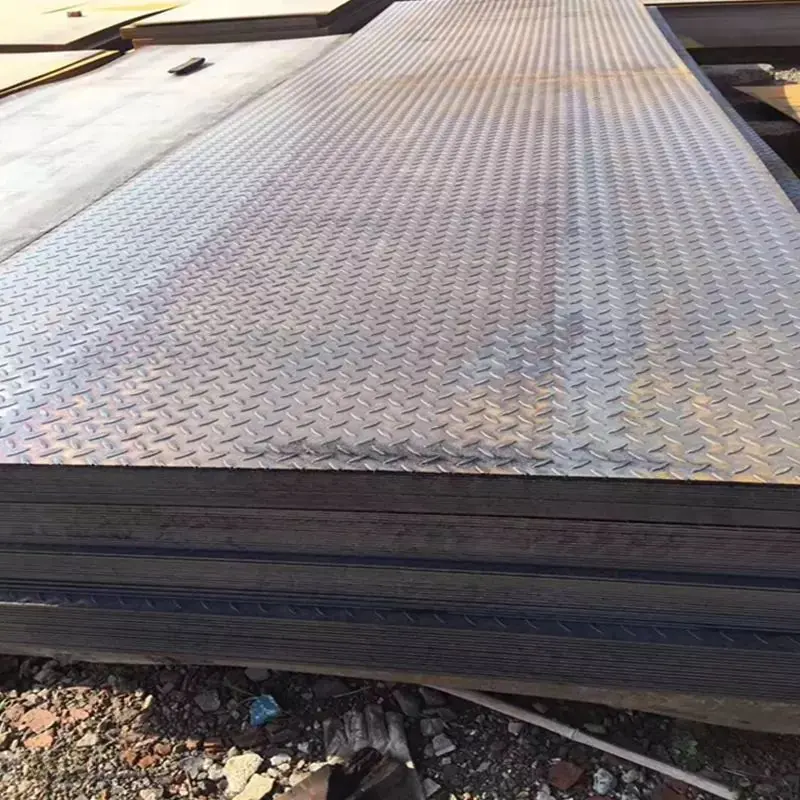 Stacked diamond-pattern steel checker plates stored outdoors on gravel ground