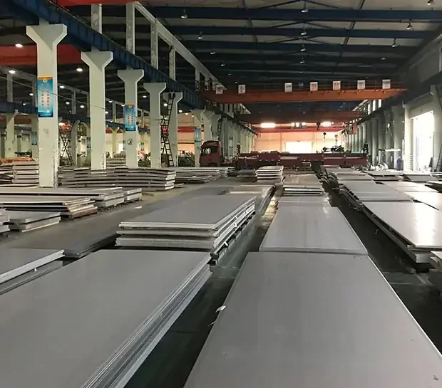 Industrial warehouse interior with rows of large metal sheets stacked on the floor