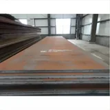 Stacked weathering steel plates with white stenciled mill markings inside a warehouse