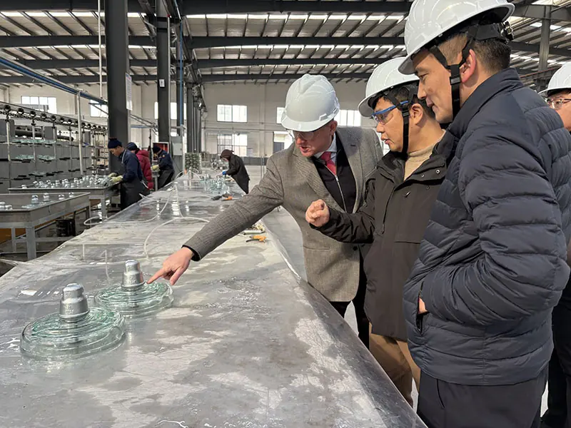 Pradex representatives reviewing finished toughened glass insulator discs during a factory audit